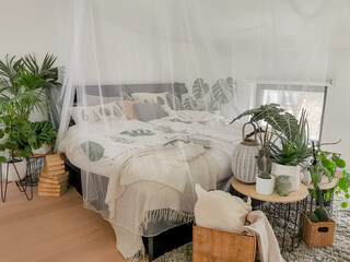 Bright white bedroom filled with numerous houseplants and flooded in natural light