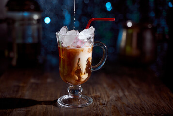 Cold coffee with milk on a wood board. Blue blurred background