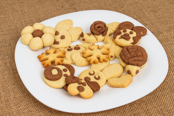 homemade cookies in the shape of dog, heart, elephant, butterfly, snowflake, slug, turtle, heart, rabbit, chamomile and owl in the tray. animal shaped cookies made for children.