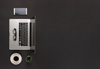 Flat lay of laptop on abstract dark black modern office desk with cup of coffe and big copy space
