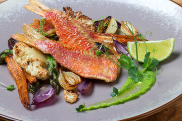 Sea bass with grilled vegetables, carrots, garlic, cauliflower, asparagus and decorated peas microgreens