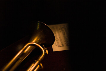 Trumpet resting closeup with sheet music in dark nightclub.