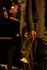 Jazz musician wearing suit playing trumpet in a dark warm night club.