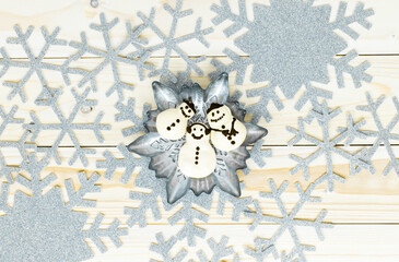 Snowflake meringue in snowflake plate and silver gray snowflakes, snowflake frame on light wooden background