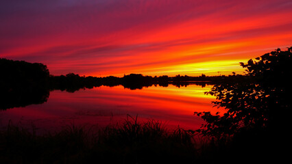 Symmetry of the sky in a lake at sunrise. Clouds reflecting on the water. Holiday landscape by the sea. Quiet relaxing scene with a beautiful colorful sky.