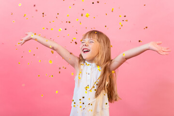 A little white girl is happy, confetti is showered on her, a holiday, a party, a greeting. on a pink background