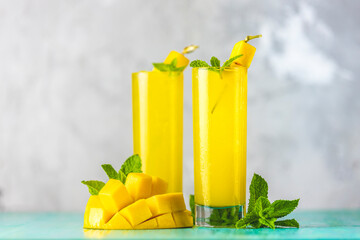 Refreshing summer cocktails made of mango, cold drink or a drink with ice on a blue gray...