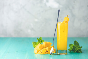 Refreshing summer cocktails made of mango, cold drink or a drink with ice on a blue gray background. Fresh summer ice cold mango cocktail or juice with mint  and mango fruit