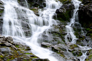 Fototapeta na wymiar clean fresh water stream running down mountain side in summer landscape