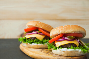 Delicious classic burgers on wooden serving board. Fast food, junk eating concept.