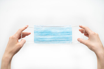 hands hold a disposable protective mask on a white background