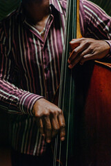 African American jazz musician hands playing upright bass in a dark club. - obrazy, fototapety, plakaty