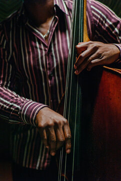 African American jazz musician hands playing upright bass in a dark club.