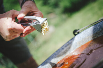 Adding pressed garlic into goulash soup on the garden party.