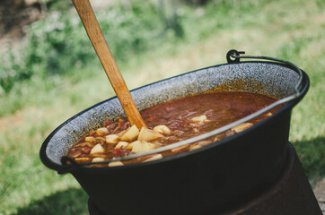 The photo shows mixing of goulash on the garden party in vintage style.