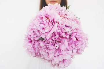 Woman holding beautiful bunch of fresh pink peony flowers in full bloom.
