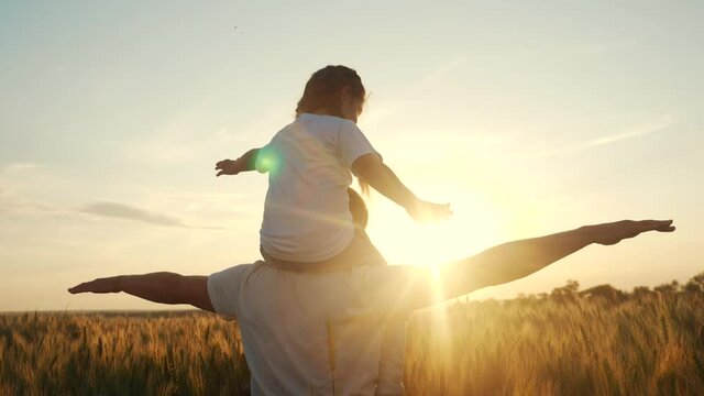 dream future concept. kid girl daughter sits on father neck play in superhero aviator pilot. silhouette at sunset. happy family people in the park. parent dad and a lifestyle small child playing