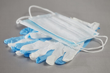 Blue and white medical gloves and medical masks on a gray background