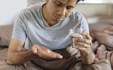 Asian men take medication to relieve illness in the bedroom.