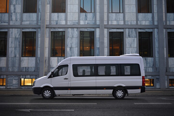 Minibus of corporate transportation of staff in the background of a business center in a business...