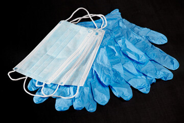 Blue medical gloves and blue medical masks on a black background
