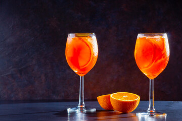 Aperol spritz cocktail on dark background. Two glasses of aperol spritz with orange slised. Summer cocktail in glass. Copy space