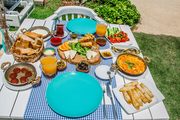 Concept promotional morning breakfast in the hotel, tasty Egg Benedict,Turkish and French Breakfast, tea and orange juice. near swimming pool in the garden