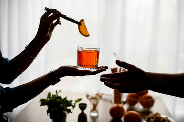 female hands carefully holds glass with cocktail and decorates it and outstretched male hand