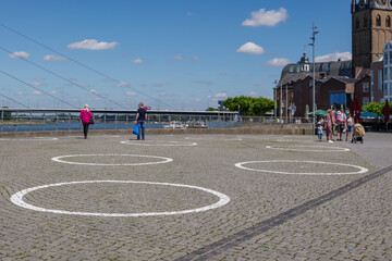 Selected focus at  group of White circles which are drawn on Burgplatz square nearby Rhine River, for concept of Social Distancing and new normal with epidemic of COVID-19 in Düsseldorf, Germany.
