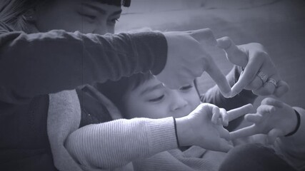 Asian mam and her mixed race son sitting on sofa making love signs, Mother and son relaxing and having fun at home in black and white retro filter, Multi ethnic of family concept
