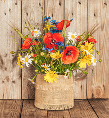 A Bouquet of Wild Flowers in a Vase on a Rustic Background. Vintage scenery.