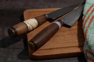 Tow Big kitchen knife with wood and handle handle lying on an old cutting board