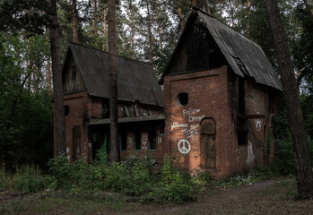 Fototapeta na wymiar The ruins of an abandoned brick house with graffiti in the forest