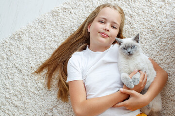 A child with a cat at home. Little girl with an animal.