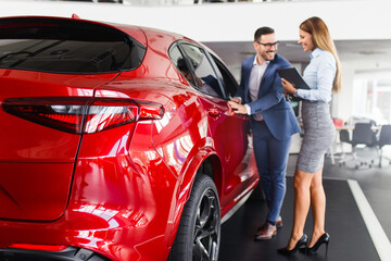 Young handsome man choosing a new car at car showroom..