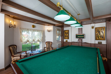 Billiard room interior. Green table for game. Old german style design. Brown wooden decor on the...