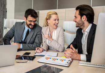Businessmen and businesswoman laughing and making jokes while at work