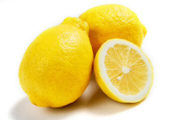 Two whole lemons and one half lemon isolated on a white background.