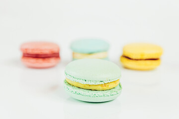 Obraz na płótnie Canvas Sweet almond colorful pastel pink blue yellow green macaron or macaroon dessert cake isolated on white background. French sweet cookie. Minimal food bakery concept Copy space