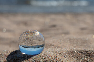 Fototapeta na wymiar Sunny day at the beach through a lens ball. Sea and sandy beach Finland. The Gulf of Finland