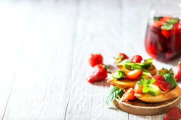 Fresh berry drink on a summer day and bruschetta with strawberries and avocado salsa. Delicious snacks, balanced nutrition.