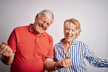Senior beautiful couple standing together over isolated white background very happy and excited doing winner gesture with arms raised, smiling and screaming for success. Celebration concept.