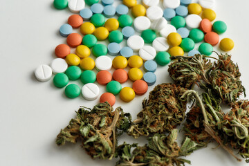 Close up of medical marijuana buds and colorful pills over white background. Concept of herbal, alternative medicine