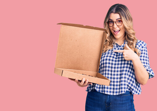 Young caucasian woman holding delivery pizza box pointing finger to one self smiling happy and proud