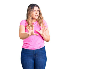 Young caucasian woman wearing sportswear afraid and terrified with fear expression stop gesture with hands, shouting in shock. panic concept.