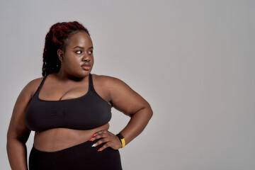 Feel free. Plump, plus size african american woman in black sportswear looking aside while standing...