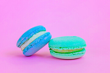 Sweet almond colorful unicorn blue green macaron or macaroon dessert cake isolated on trendy pink pastel background. French sweet cookie. Minimal food bakery concept Copy space