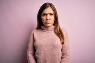 Beautiful young woman wearing turtleneck sweater over pink isolated background skeptic and nervous,...