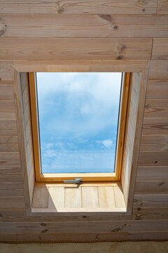 Window in the attic of a wooden house. Window in the middle of the house. The sky is visible from the window