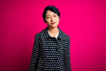Young beautiful asian girl wearing casual jacket standing over isolated pink background looking...